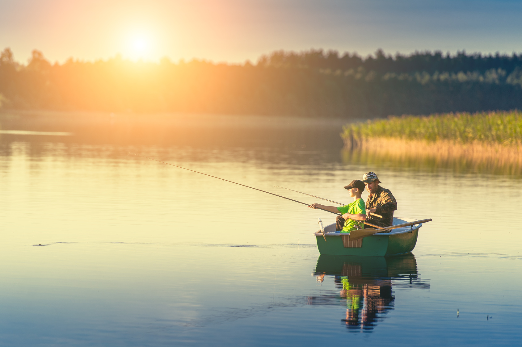 father and son catch fish from a boat at sunset - my westshore